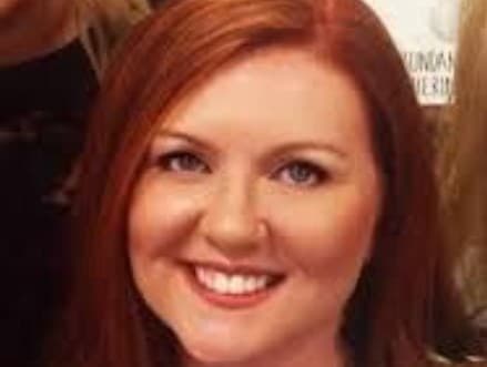 A smiling woman with long red hair.