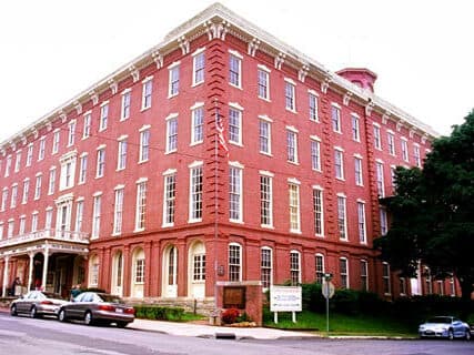 Historic red brick building with large windows and an American flag.