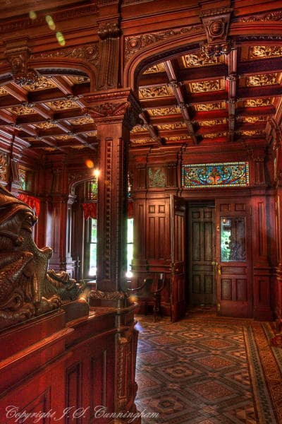 An ornate, wooden-paneled room with intricate ceilings and stained glass windows.