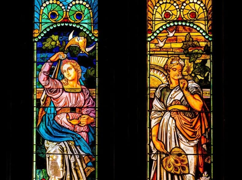 Stained glass windows depicting two female figures, one holding a bird and the other with a fan.