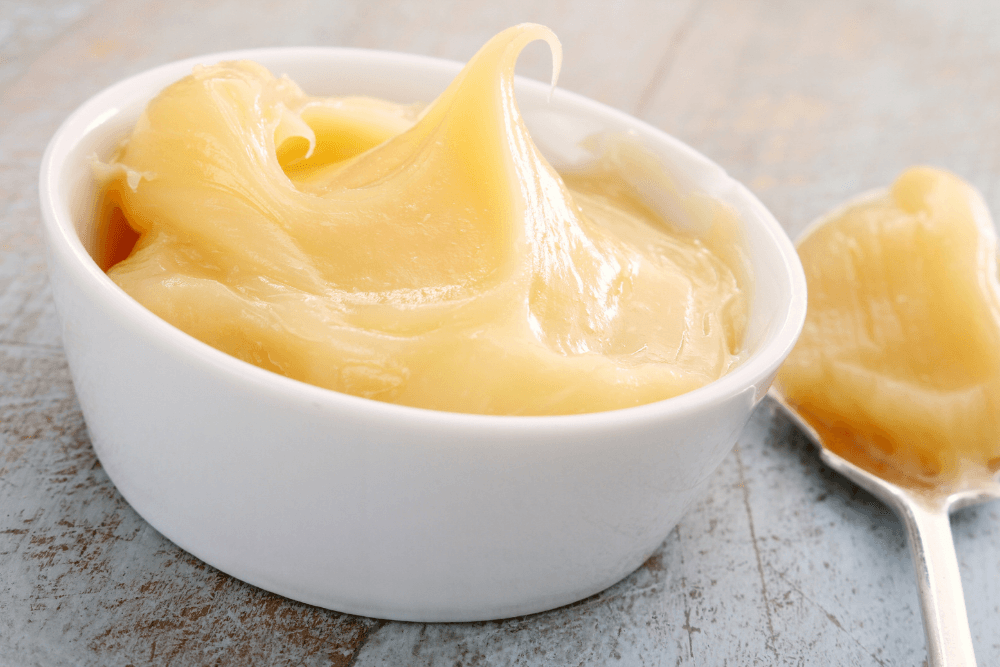 A bowl of creamy, golden butter with a spoon beside it.