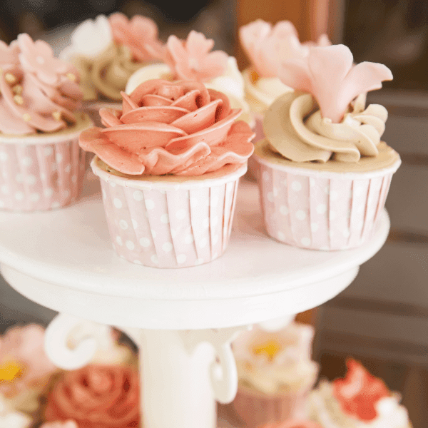 A display of elegantly decorated cupcakes with pink and beige frosting in polka-dot wrappers.
