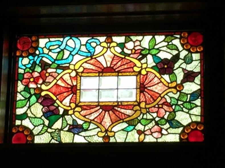 Colorful stained glass window featuring floral patterns and geometric designs.