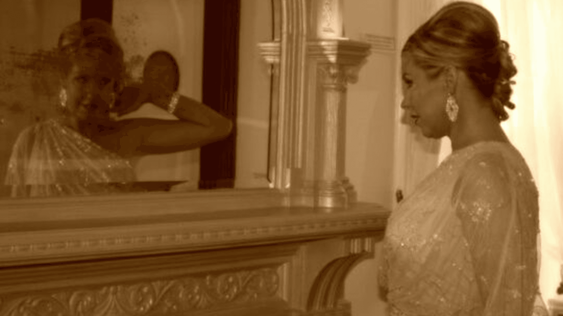 A woman in elegant attire gazes into a mirror, reflecting a graceful pose.