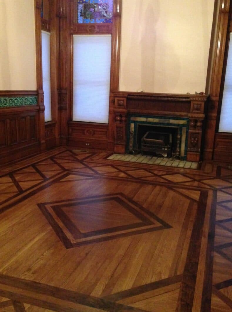 A room featuring intricate wooden flooring and a decorative fireplace.