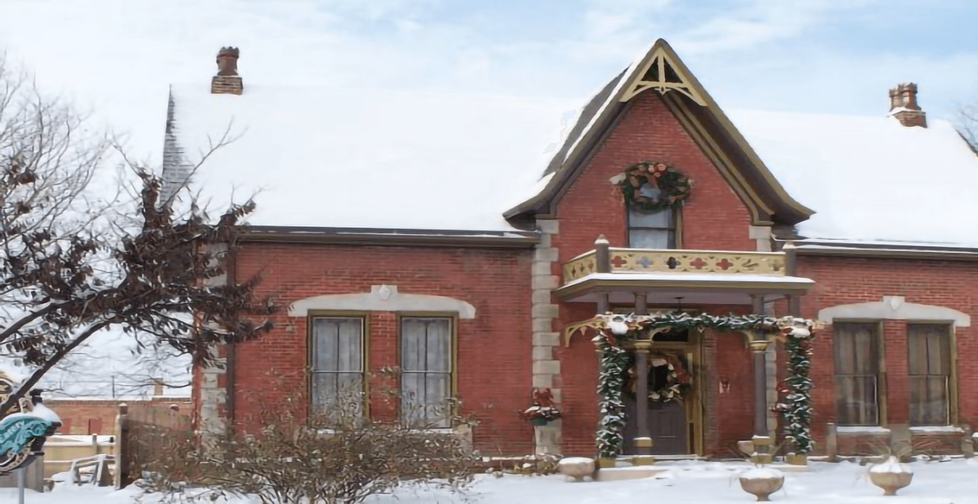 A charming brick house adorned with festive decorations and covered in snow.