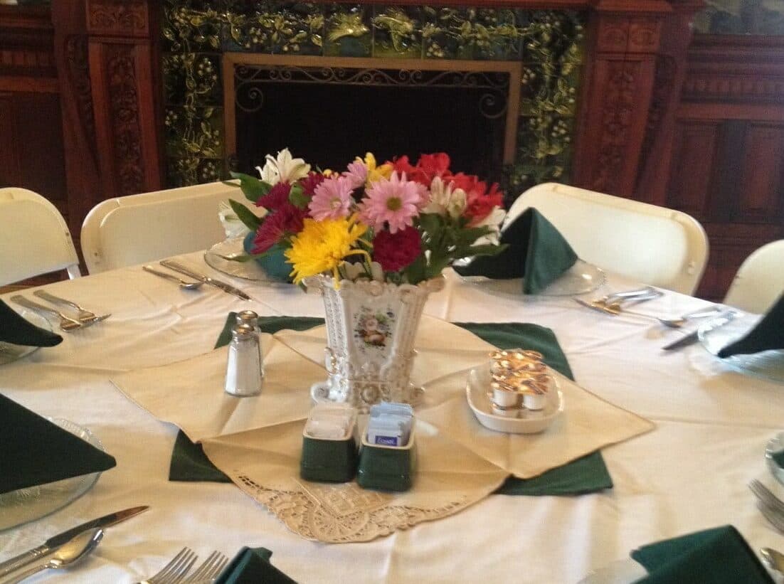 A beautifully set dining table with a floral centerpiece and green napkins.