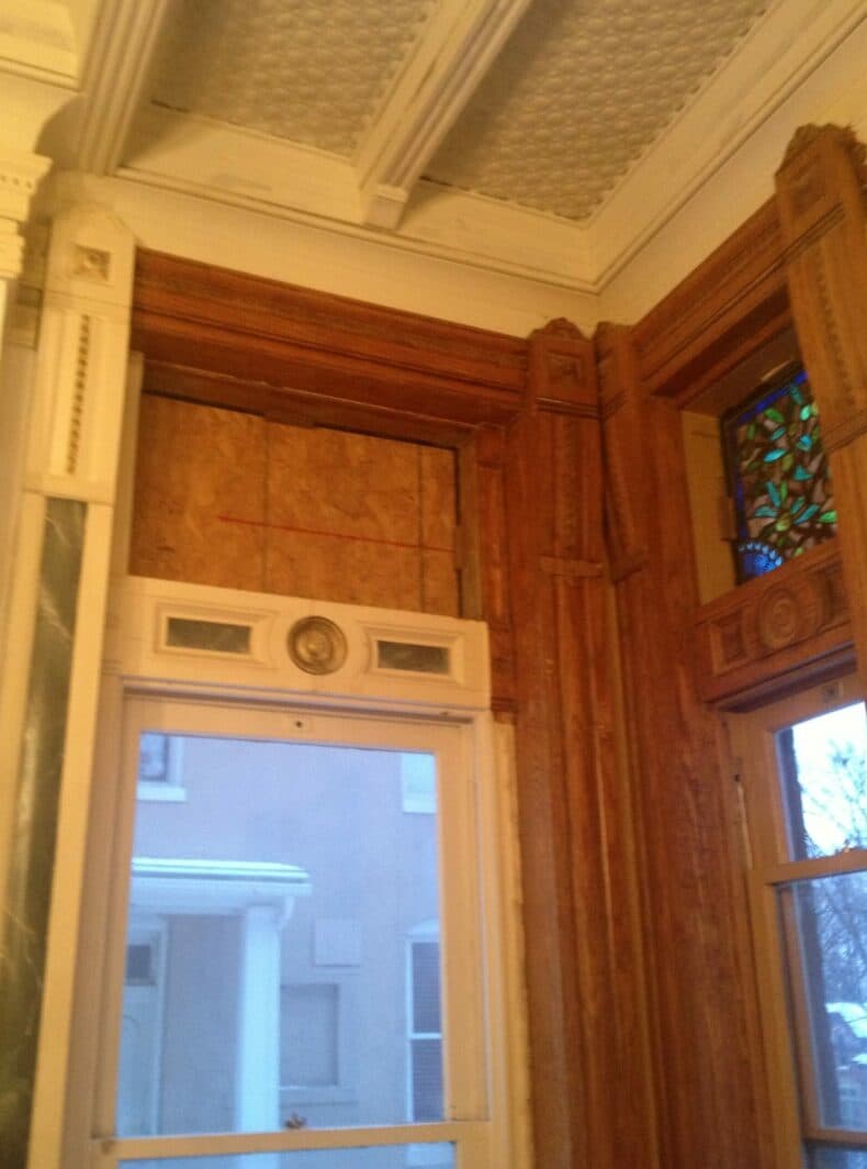 Interior corner of a vintage room featuring decorative woodwork and stained glass window.