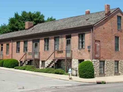 Historic brick building with stone foundation and green landscaping.