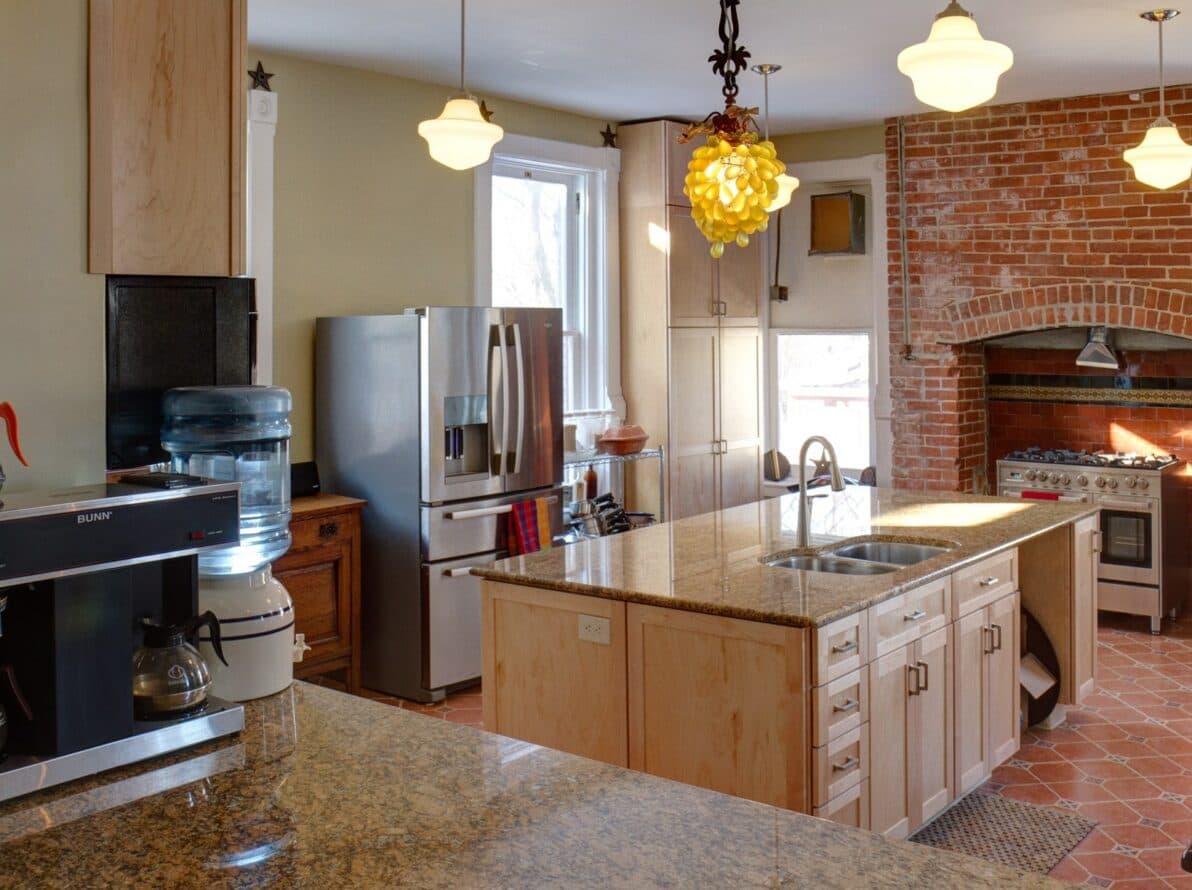 A modern kitchen featuring granite countertops, stainless steel appliances, and a stylish light fixture.